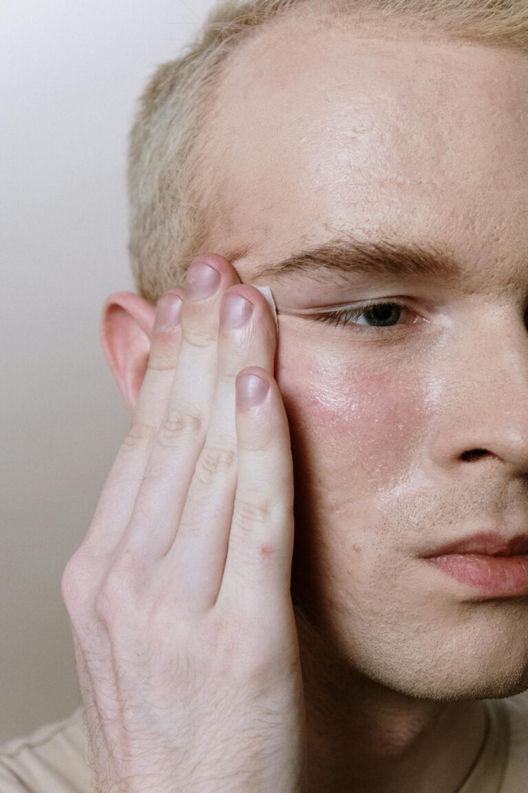 A young man applying skincare product to his cheek, emphasizing self-care and hydration.